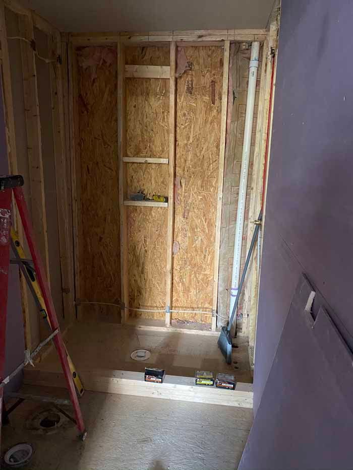 Unfinished room with exposed wood framing, OSB wall panels, and a ladder during renovation