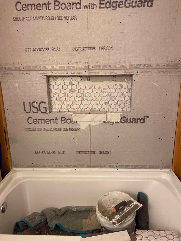 Shower base with cement board walls under construction, with tools and materials inside.
