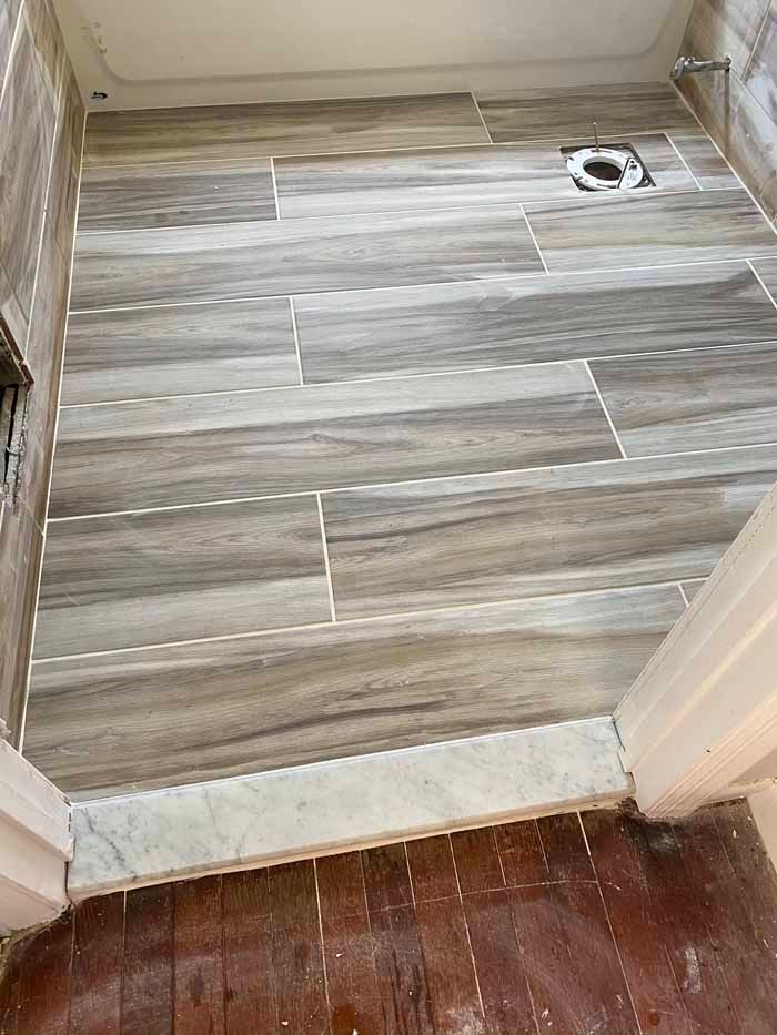 Hallway entrance with gray wood-look tile flooring and a small drain near the wall.