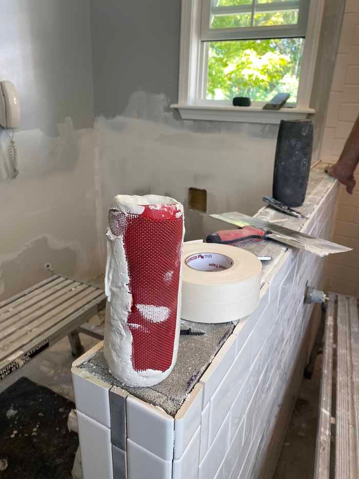 Red plastic cups stacked on a tiled ledge in a dusty, unfinished room with a window.