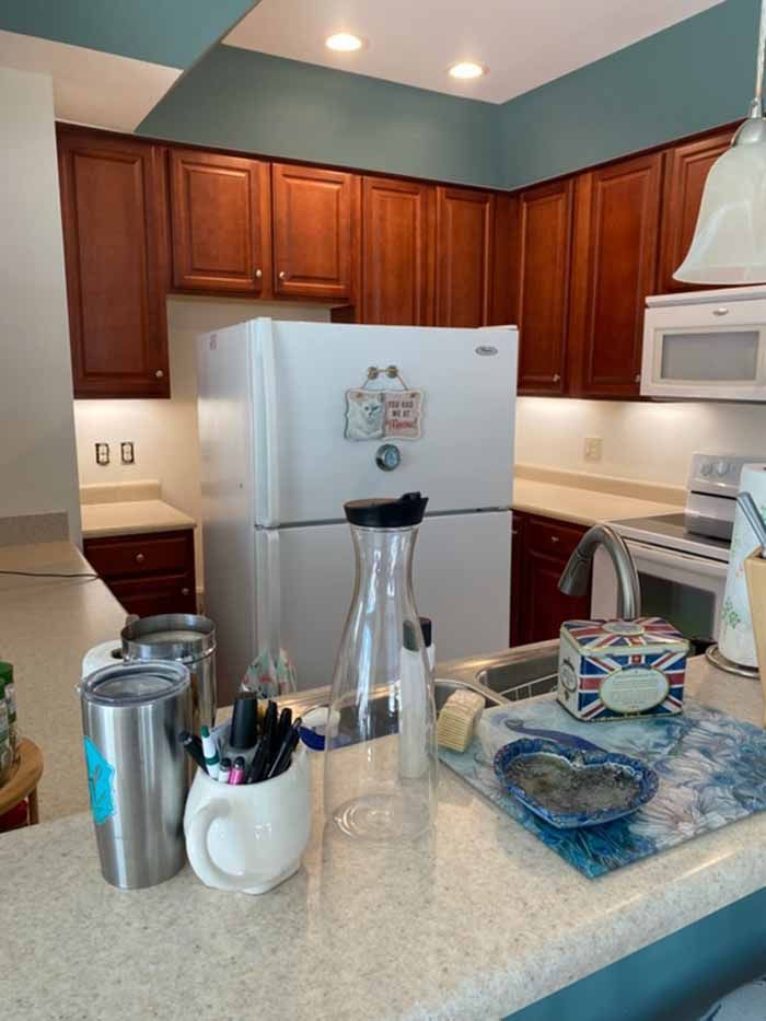 Kitchen with wood cabinets, white appliances, and a granite island holding a blender and mugs.