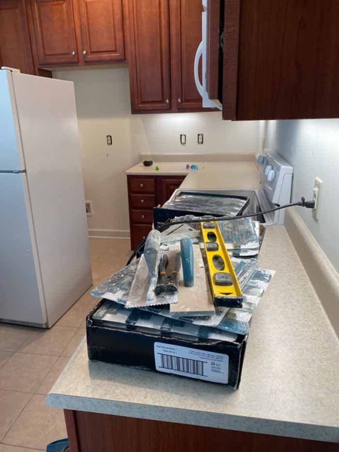 Kitchen counter with tools and a yellow level beside a stove and refrigerator in a small kitchen