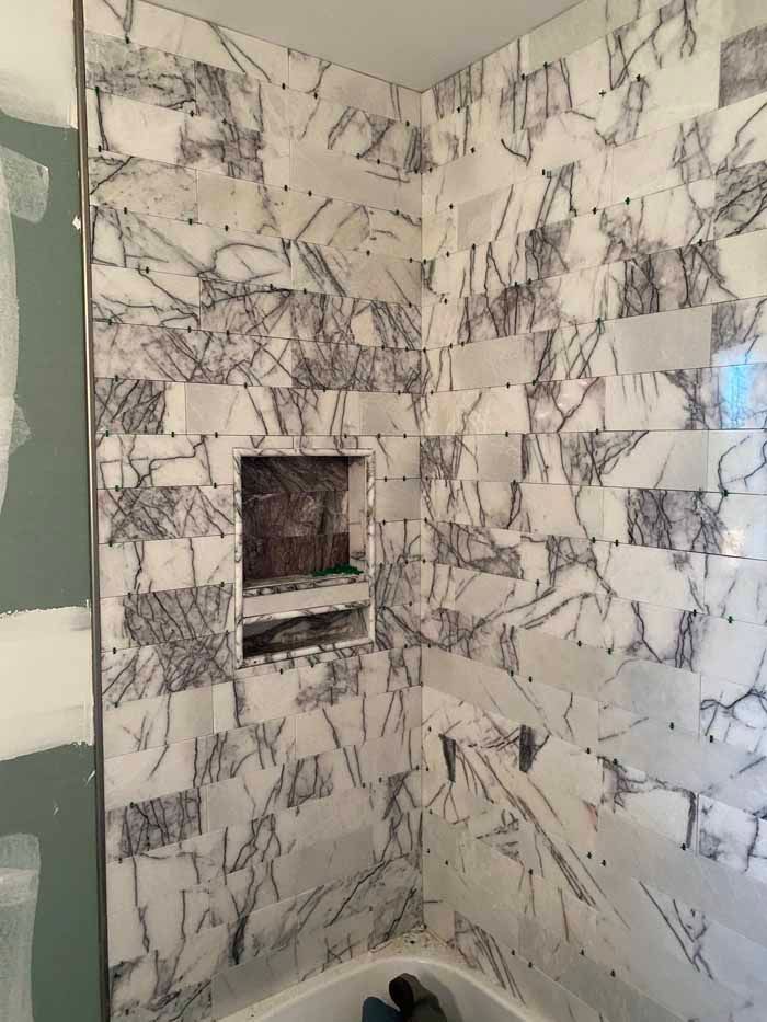Marble-tiled shower corner with a recessed niche and chrome fixtures
