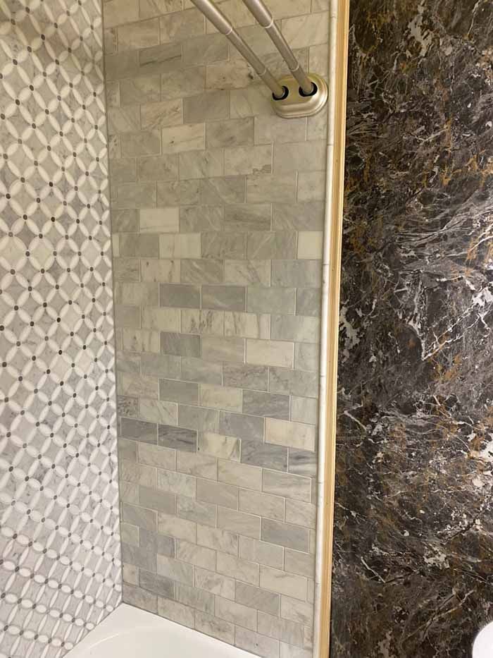 Walk-in shower with gray tile walls and patterned tile accent panel