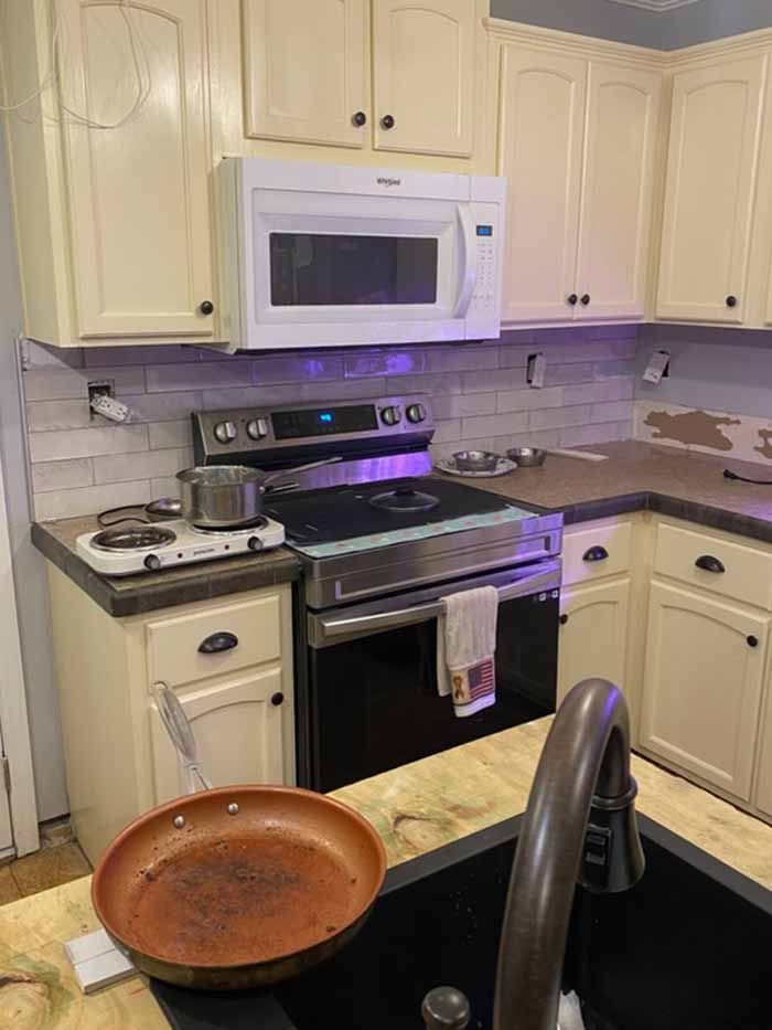 Kitchen with cream cabinets, black stove and microwave, and a bowl on the counter in the foreground.