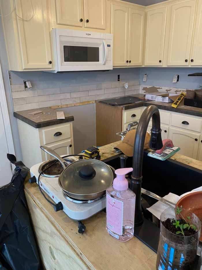 Cluttered kitchen counter with sink, cleaning items, and a microwave above the stove.