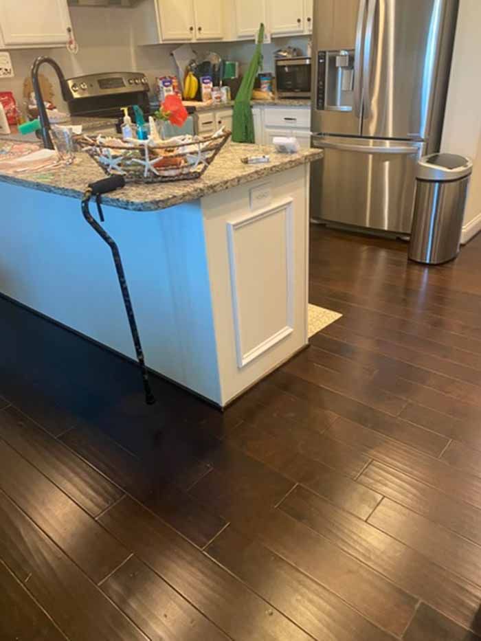 Modern kitchen with granite island, dark wood floors, stainless steel fridge, and sink area