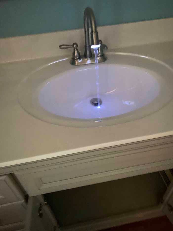 Bathroom sink with a faucet running water into a white basin.