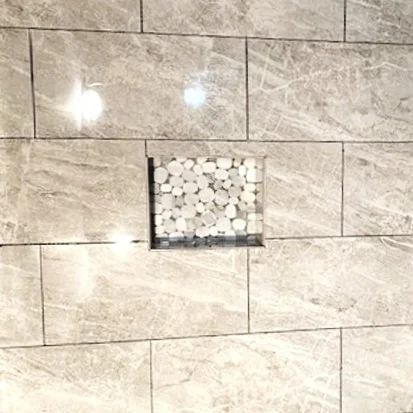 Beige tiled wall with a small square mosaic accent in the center