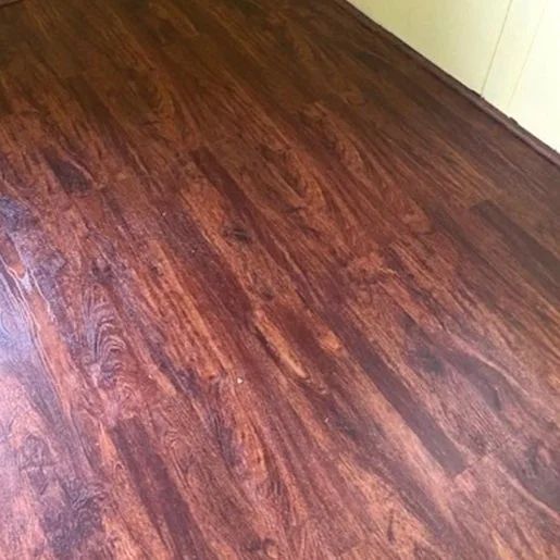 Dark wood floor with a glossy, reddish-brown finish beside a white wall.