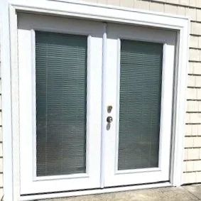 White double glass patio doors with closed blinds and silver handle