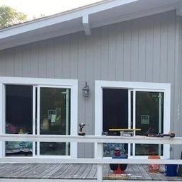 Gray house exterior with white-framed sliding doors and a wooden deck with railing