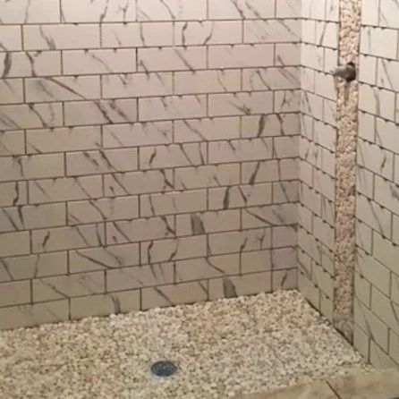 Tiled shower corner with a pebble floor and a round drain