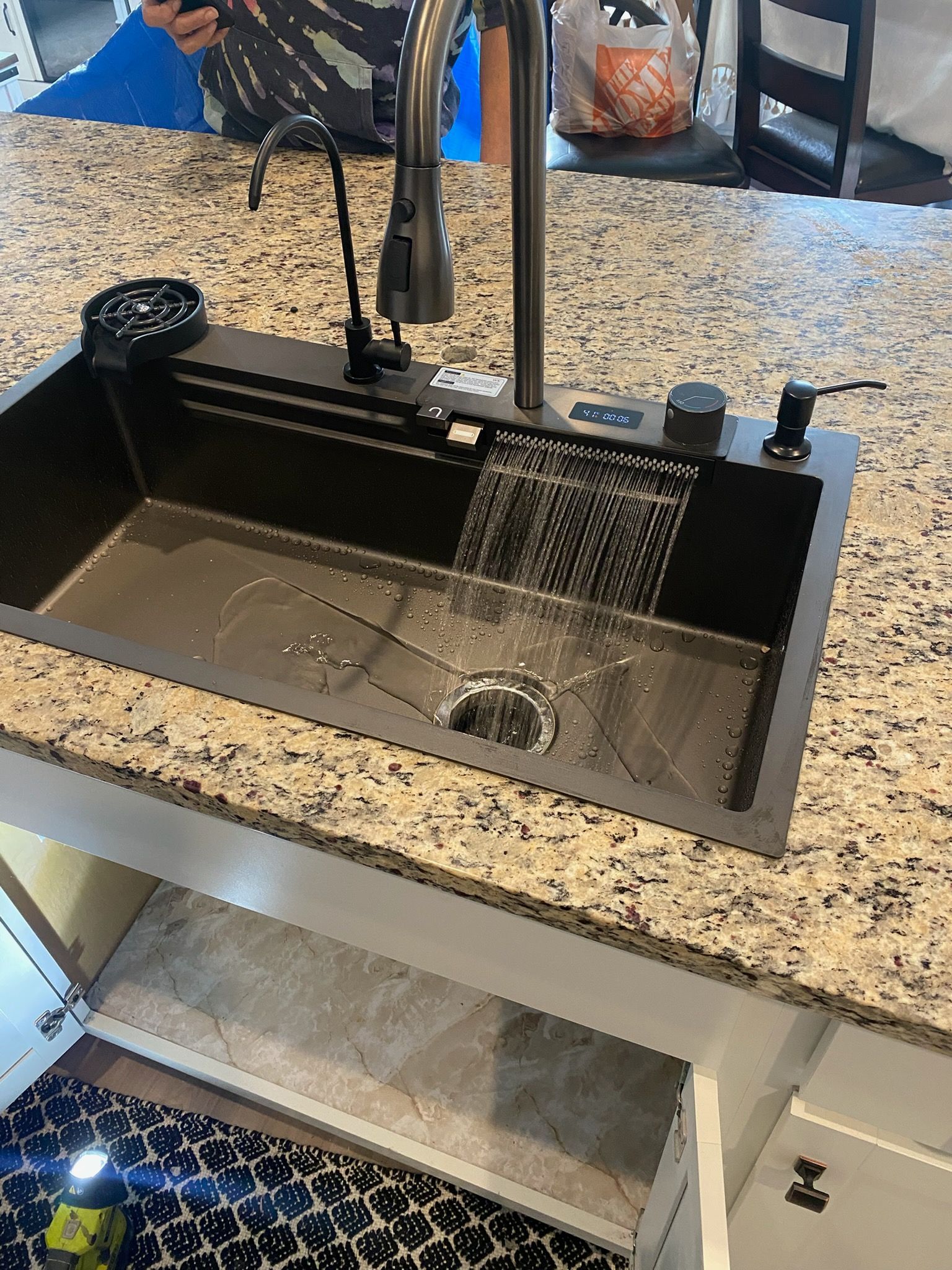 Kitchen sink with running faucet and soap dispenser in a granite countertop.