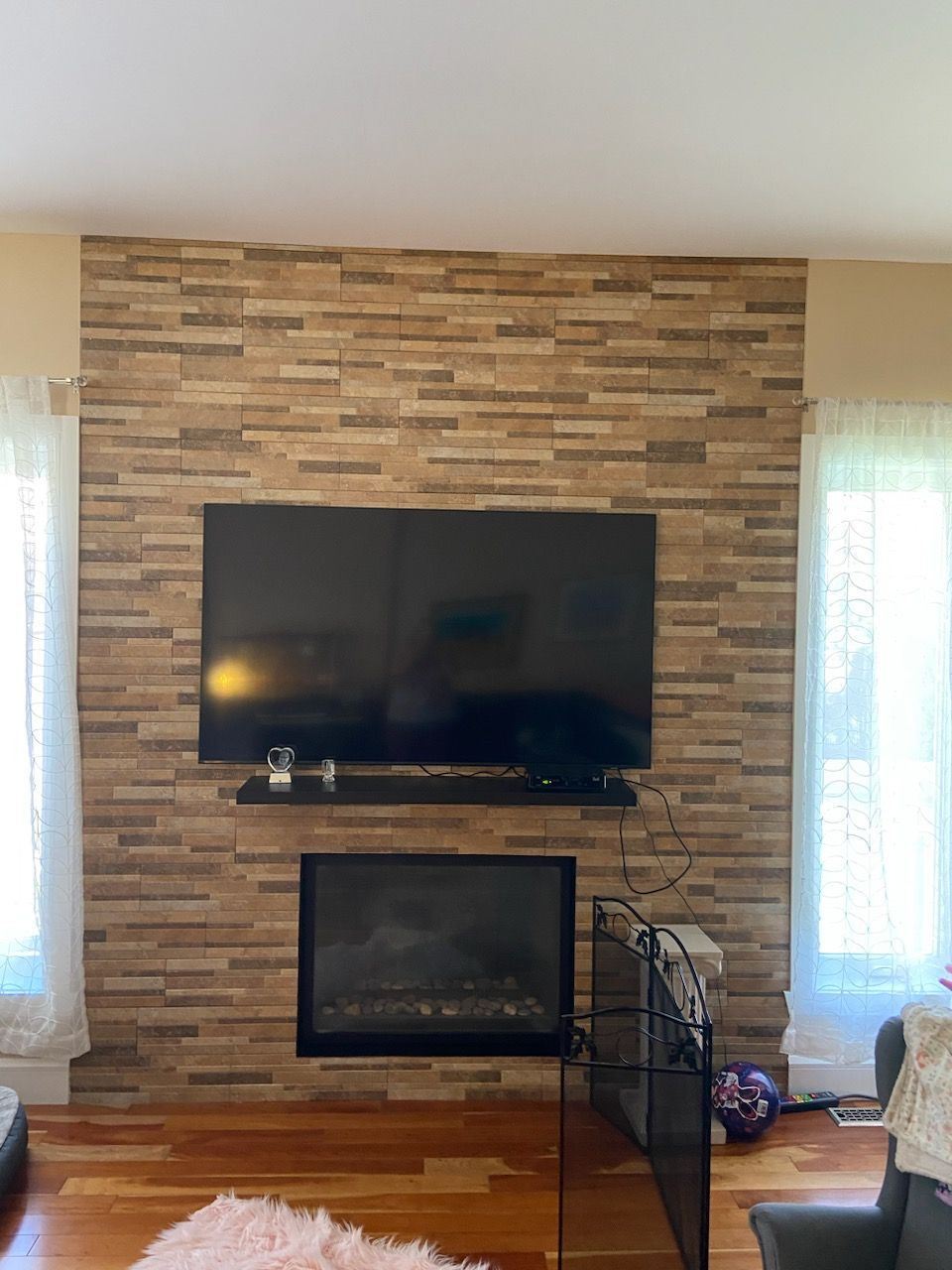 Cheminée avec un mur imitant la brique. Un téléviseur est fixé au-dessus d'une cheminée noire.