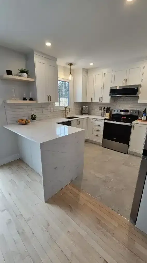Cuisine blanche avec îlot central, comptoirs en quartz, armoires blanches et parquet clair.