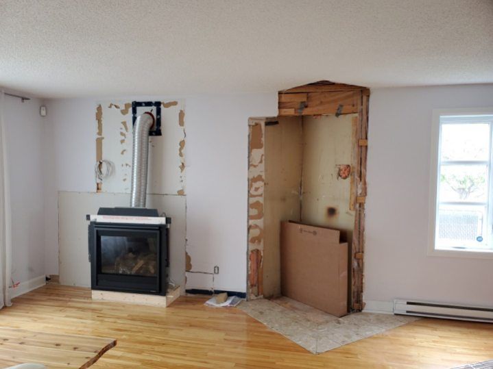 Pièce en rénovation avec cheminée et conduit de cheminée ; charpente apparente.
