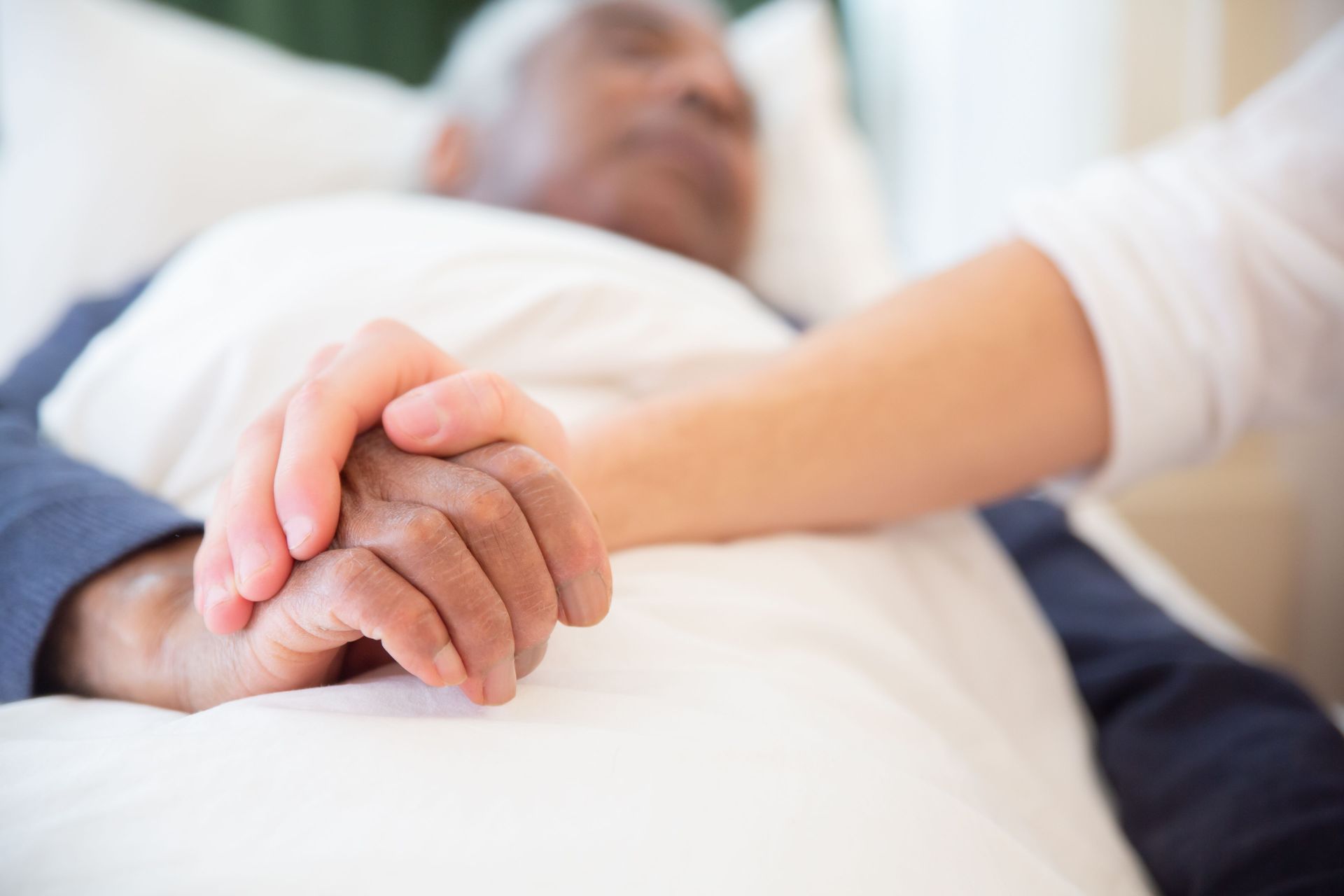 A healthcare professional in scrubs reviews paperwork with a patient at a wooden table in a home setting.