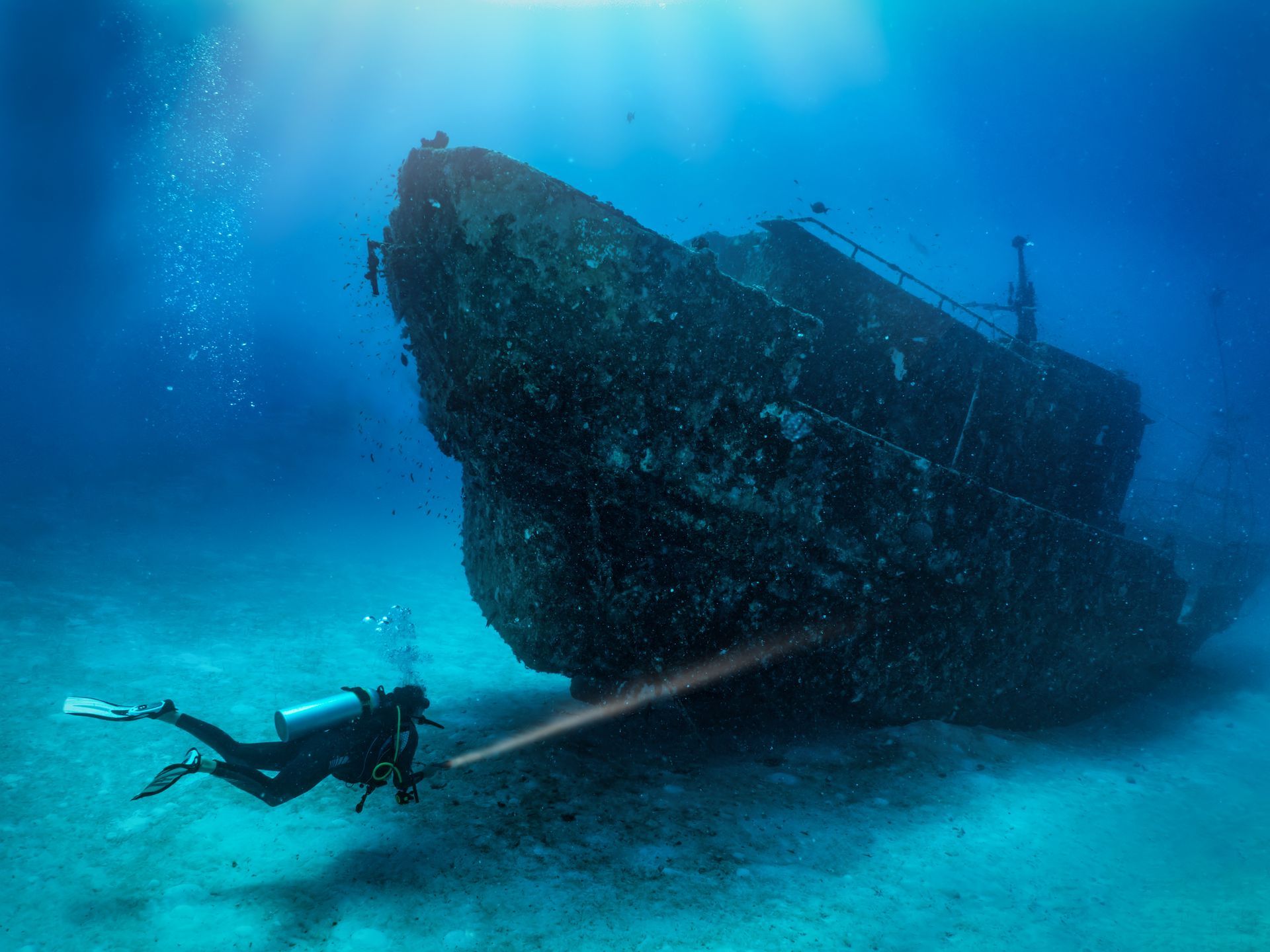A scuba diver is looking at a shipwreck in the ocean.