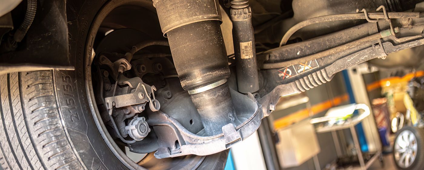Undercarriage view of a vehicle's suspension, shock absorber, and brake components.