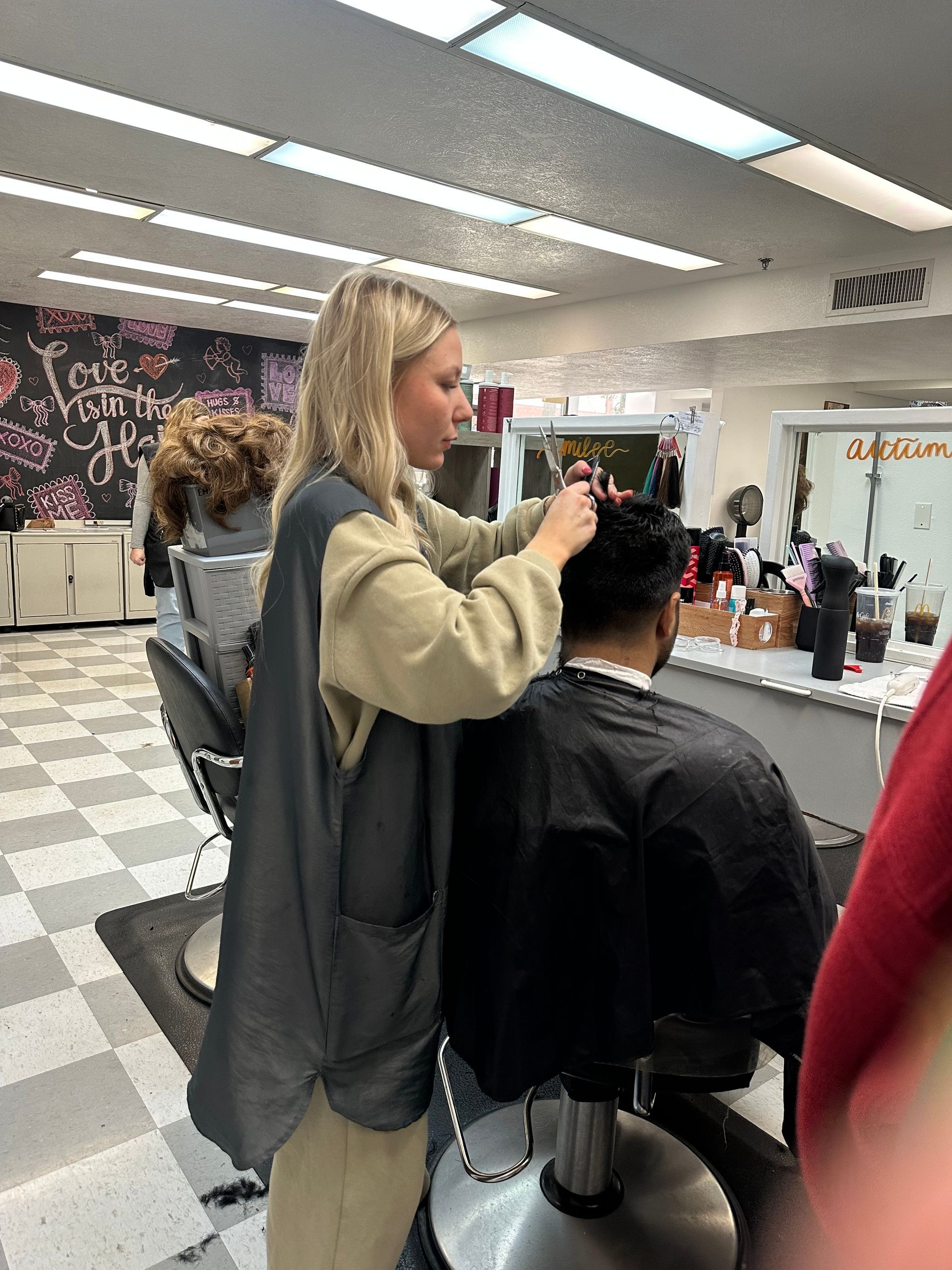 A hairstylist trims the hair of a client seated in a salon chair in front of a mirror. A hairstylist trims the hair of a client seated in a salon chair in front of a mirror.