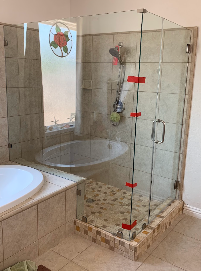 Frameless corner shower with brushed nickel hardware beside a garden tub