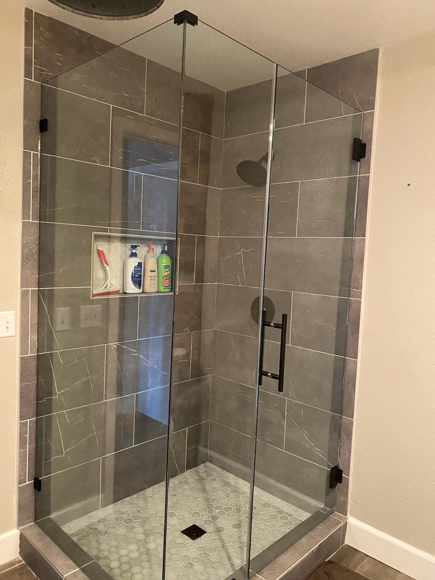 Frameless corner shower with gray tile and matte black hardware