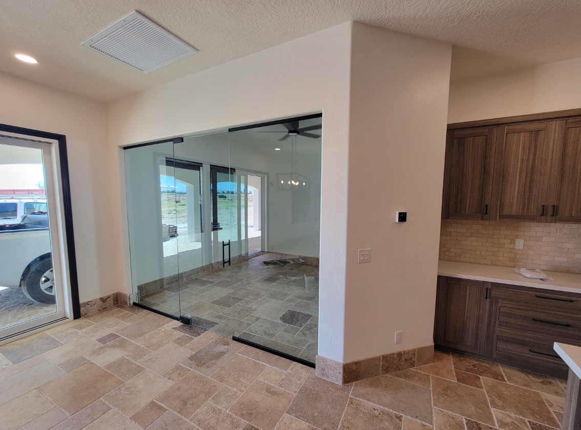 Frameless glass partition wall over travertine floor in a Hesperia home