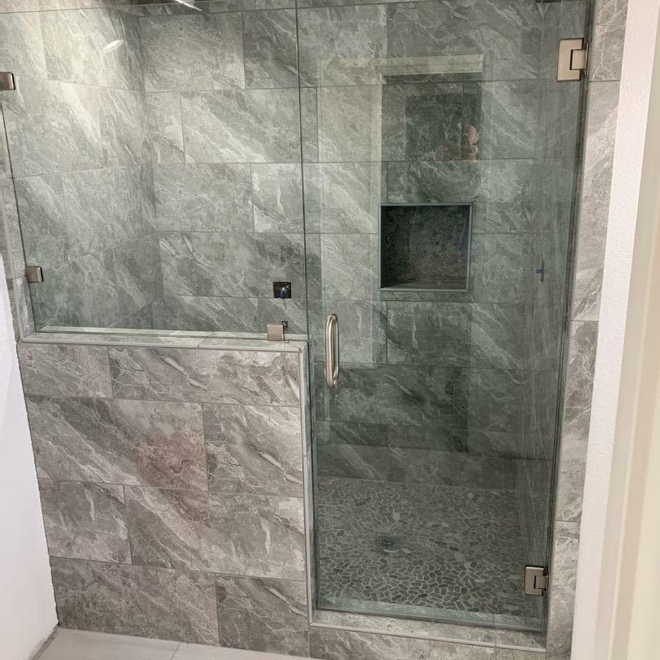 Frameless inline shower door and glass panel with gray marble tile