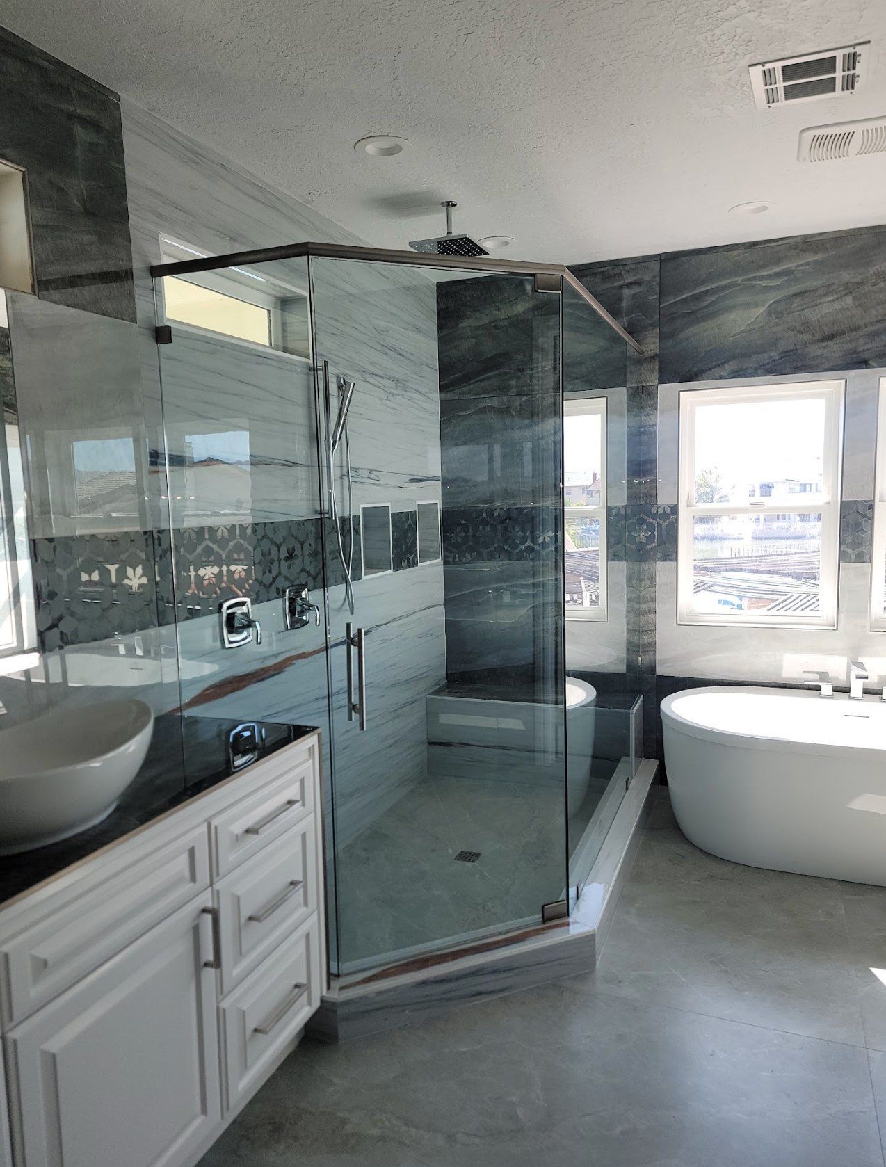 Frameless neo angle shower enclosure next to a freestanding soaking tub