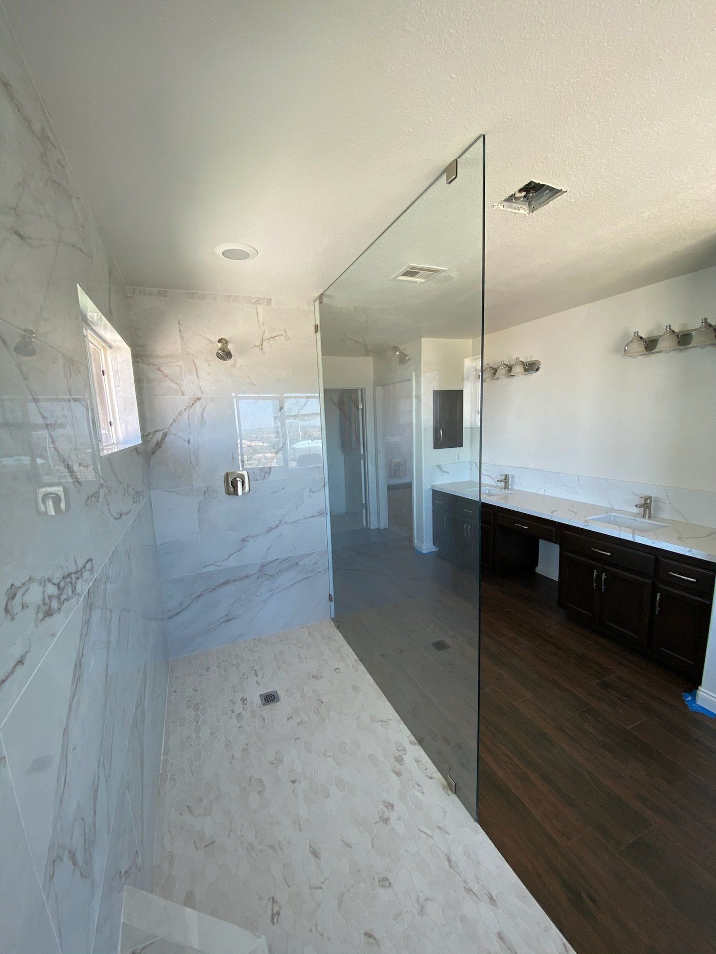 Frameless walk-in shower glass panel with marble tile by High Desert Window and Glass