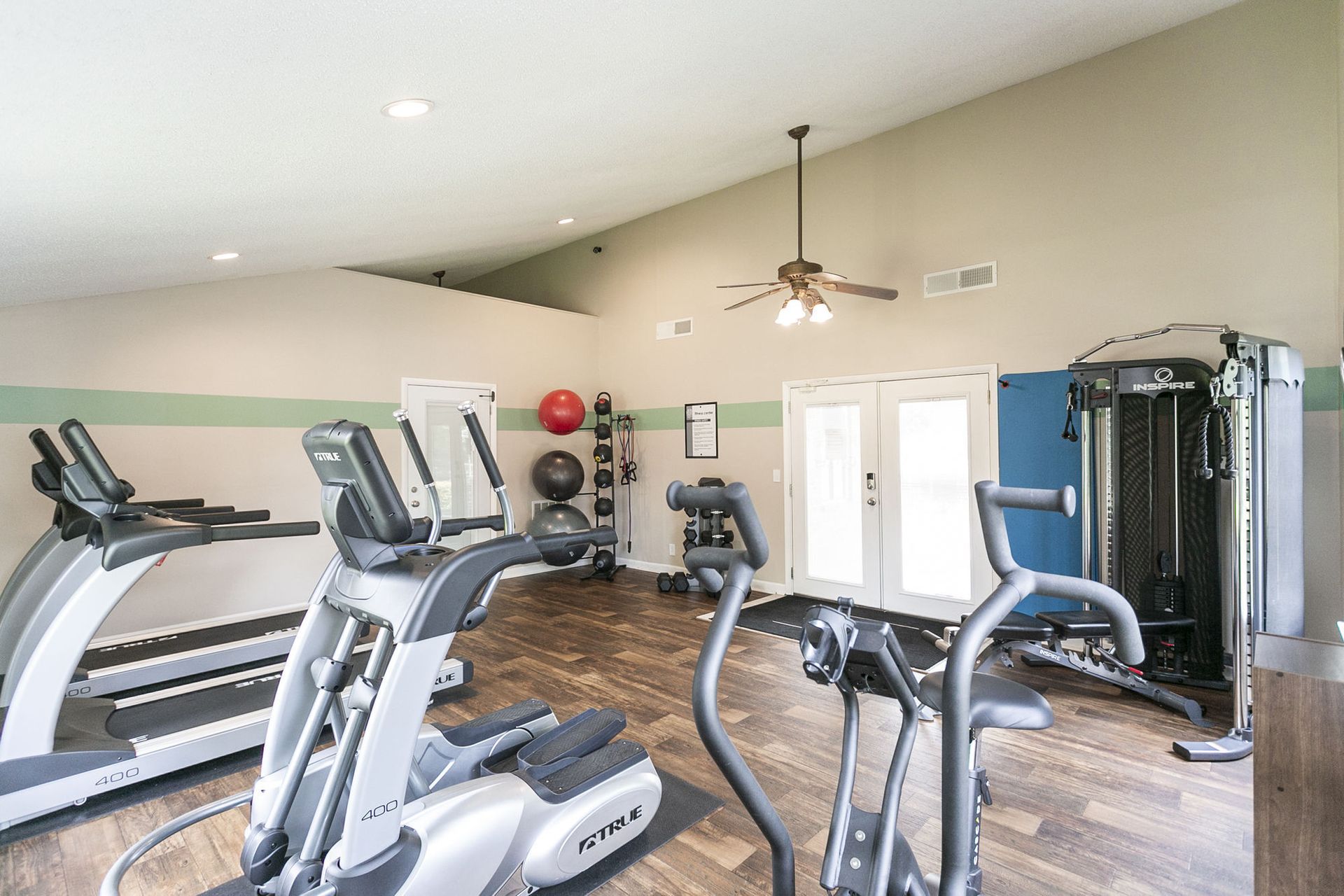 A small gym with exercise equipment including treadmills, an elliptical, a stationary bike, and a weight machine.