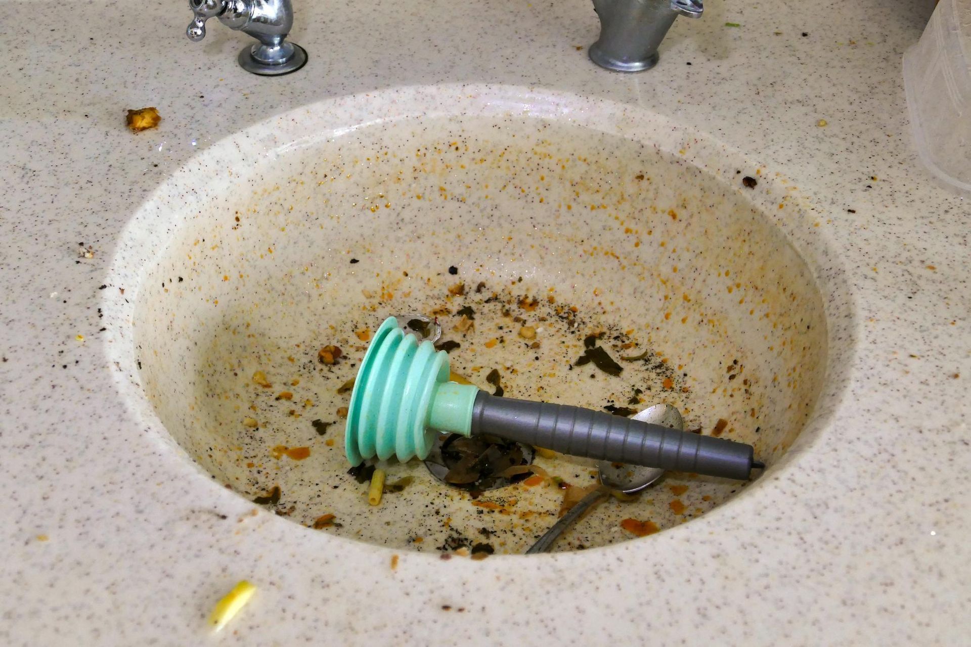 A dirty sink with a spoon in it