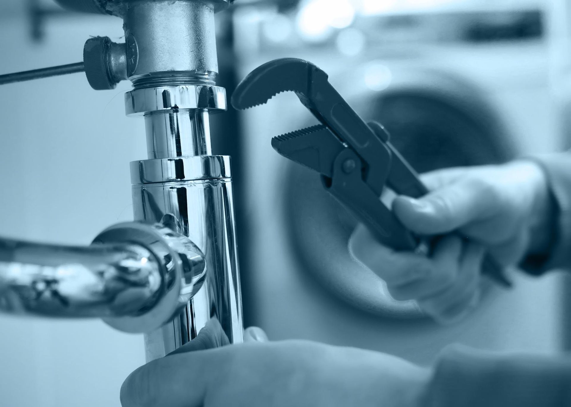 A person is fixing a pipe with a wrench.
