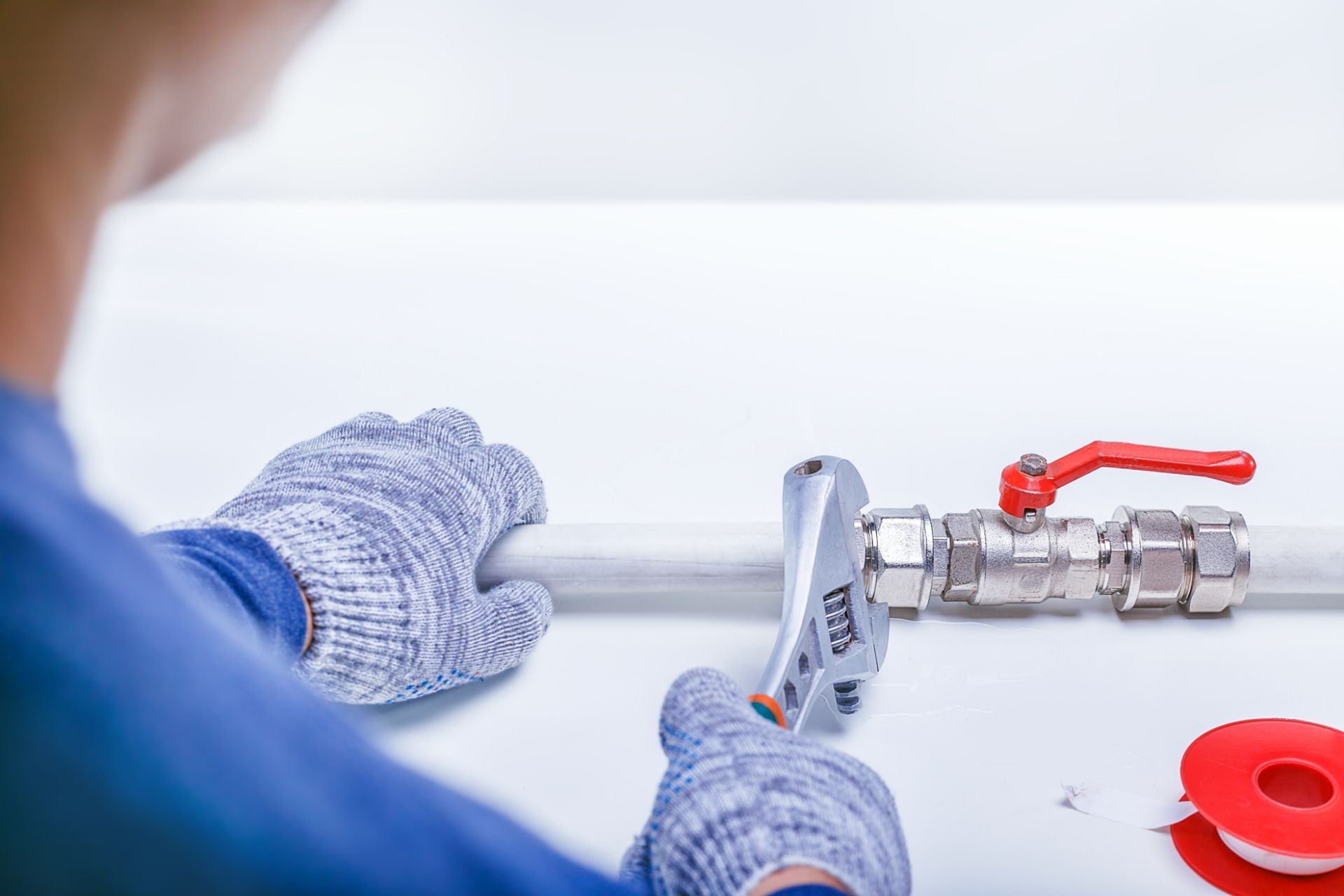 A plumber is working on a pipe with a wrench.