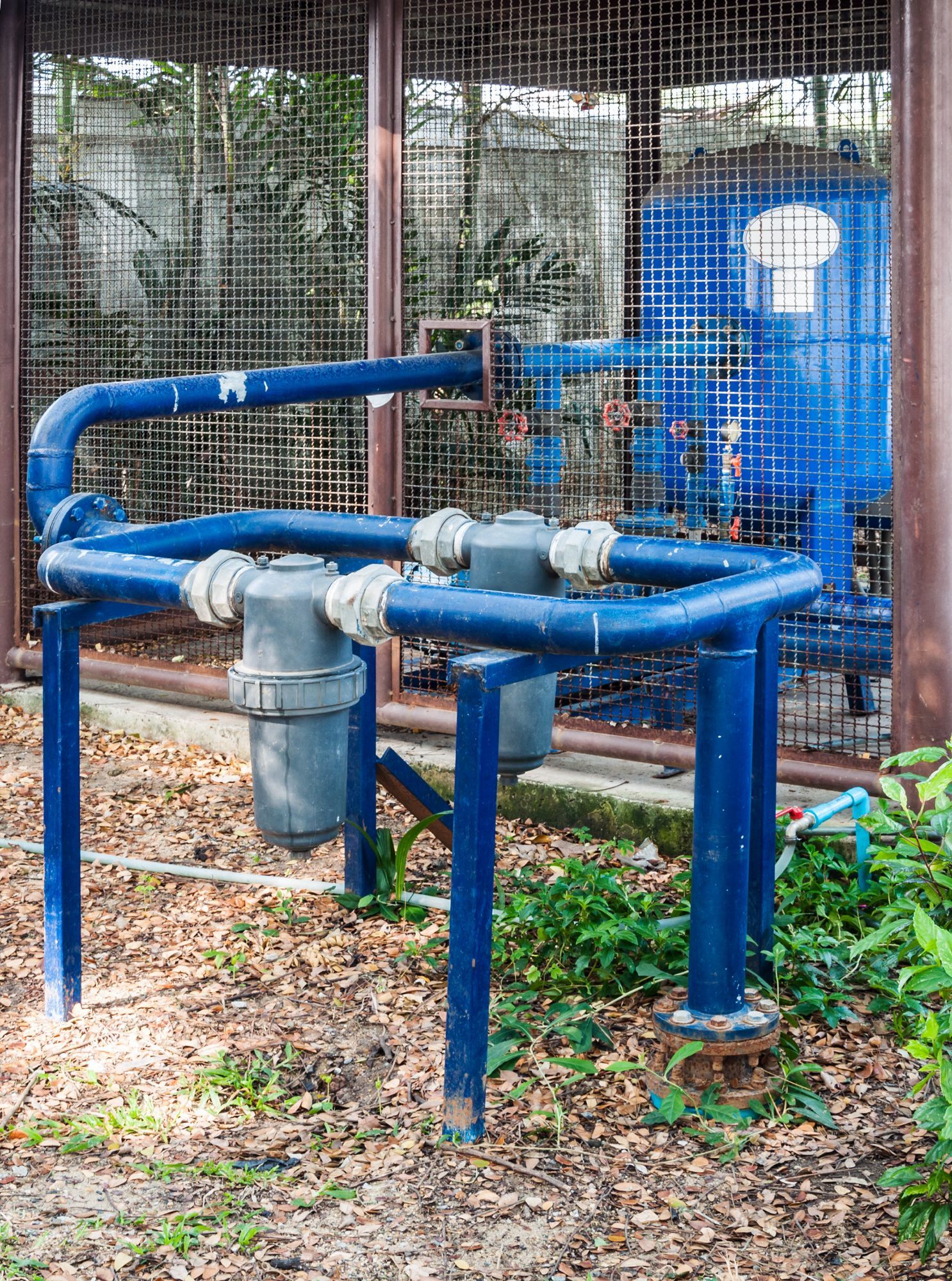 A blue pipe is sitting in the dirt next to a fence.