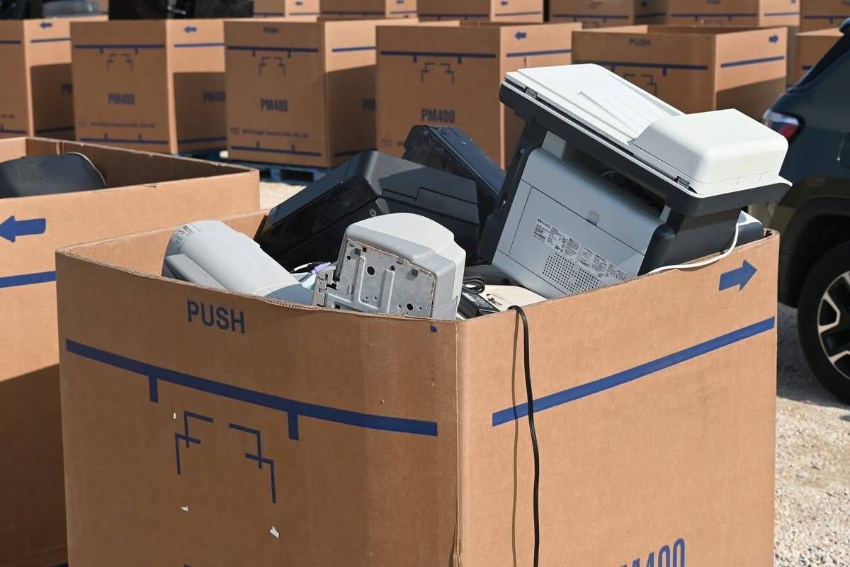 Discarded printers and office electronics collected in a cardboard recycling container
