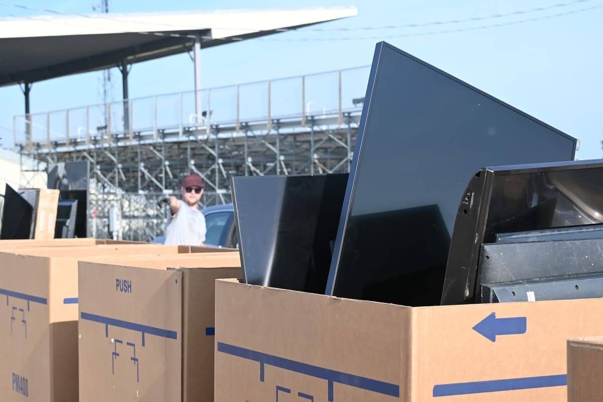Monitors and televisions collected in large boxes at an outdoor electronics recycling event