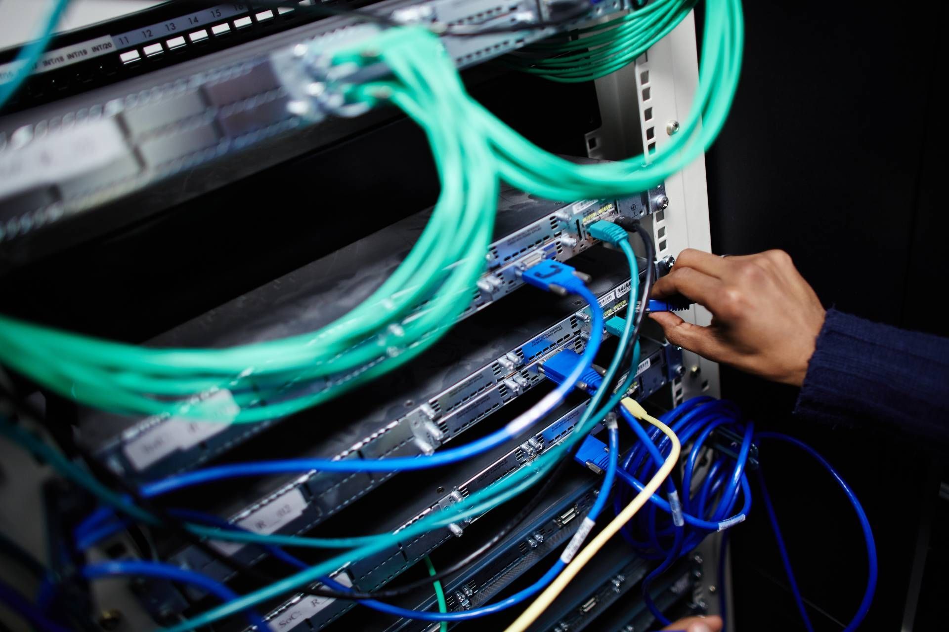 Engineer working on a business server with blue and green wires