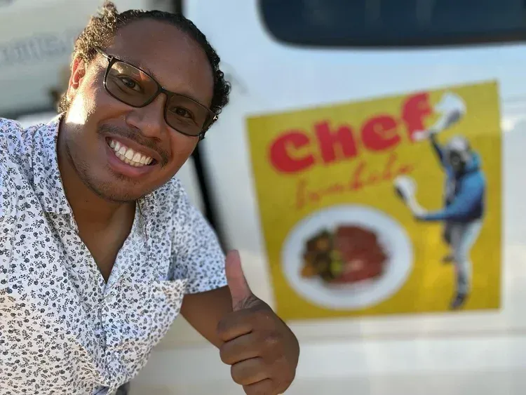 Smiling man giving a thumbs-up beside a yellow Cheez-It sign outdoors Smiling man giving a thumbs-up beside a yellow Cheez-It sign outdoors