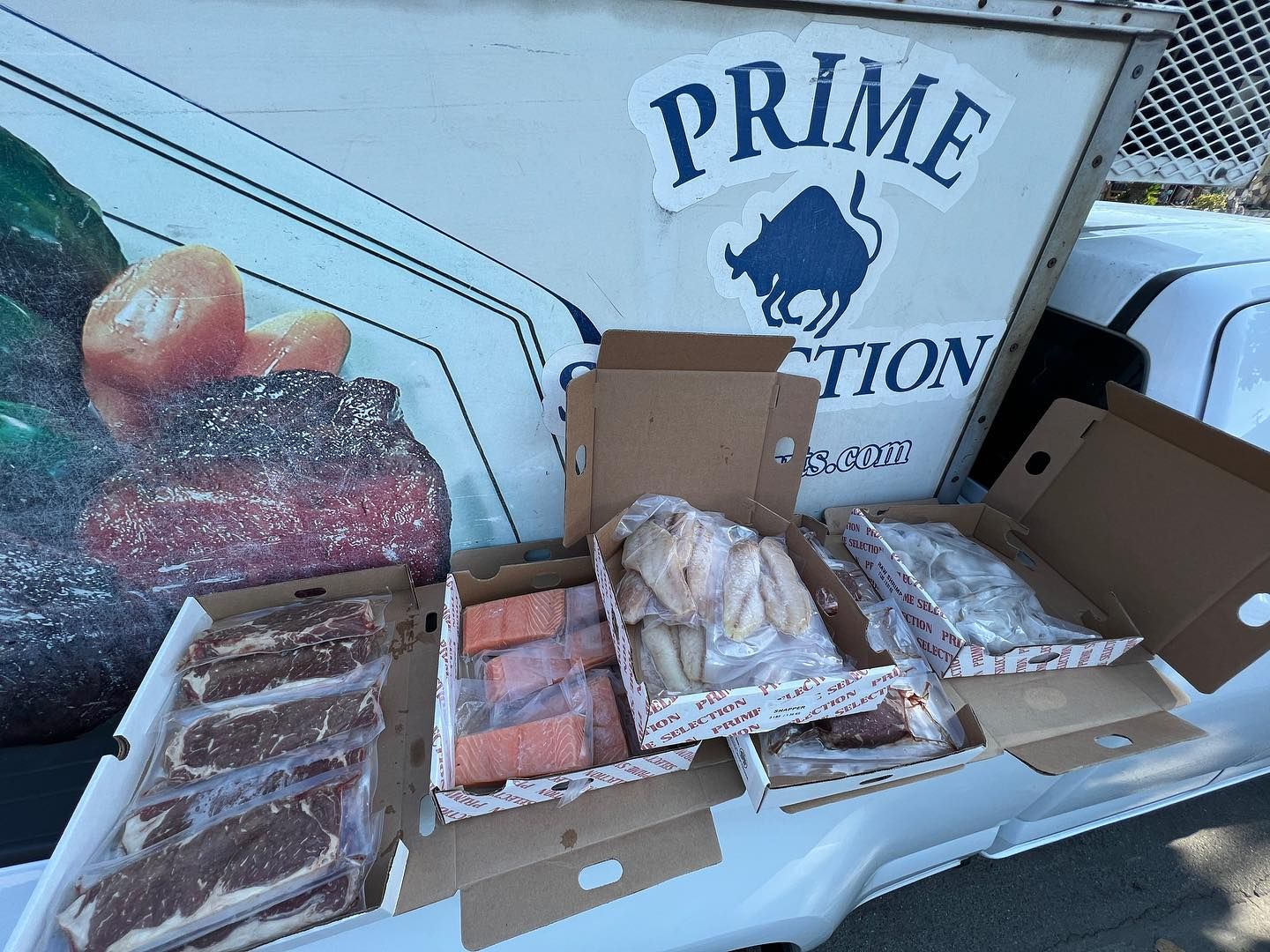 Open seafood display with assorted fish fillets and trays outside a Prime Fish Market sign Open seafood display with assorted fish fillets and trays outside a Prime Fish Market sign