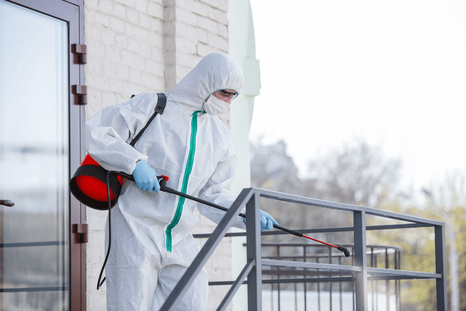 A Man in a Protective Suit is Spraying a Staircase With a Sprayer — Lighthouse Pest Control In Mullumbimby, NSW