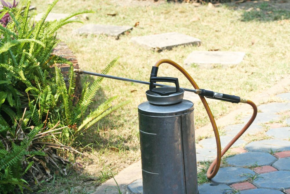 A Spray Bottle is Sitting on the Ground in a Garden — Lighthouse Pest Control In Brunswick Heads, NSW