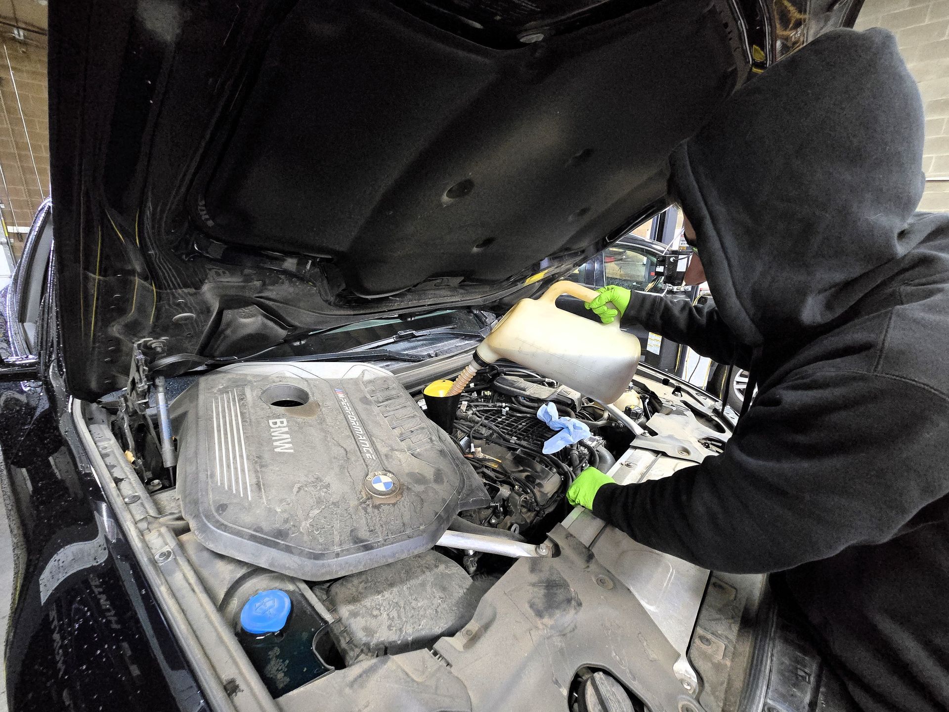 Technician performing BMW engine oil service during routine maintenance at Peak Euro Bend, Or.