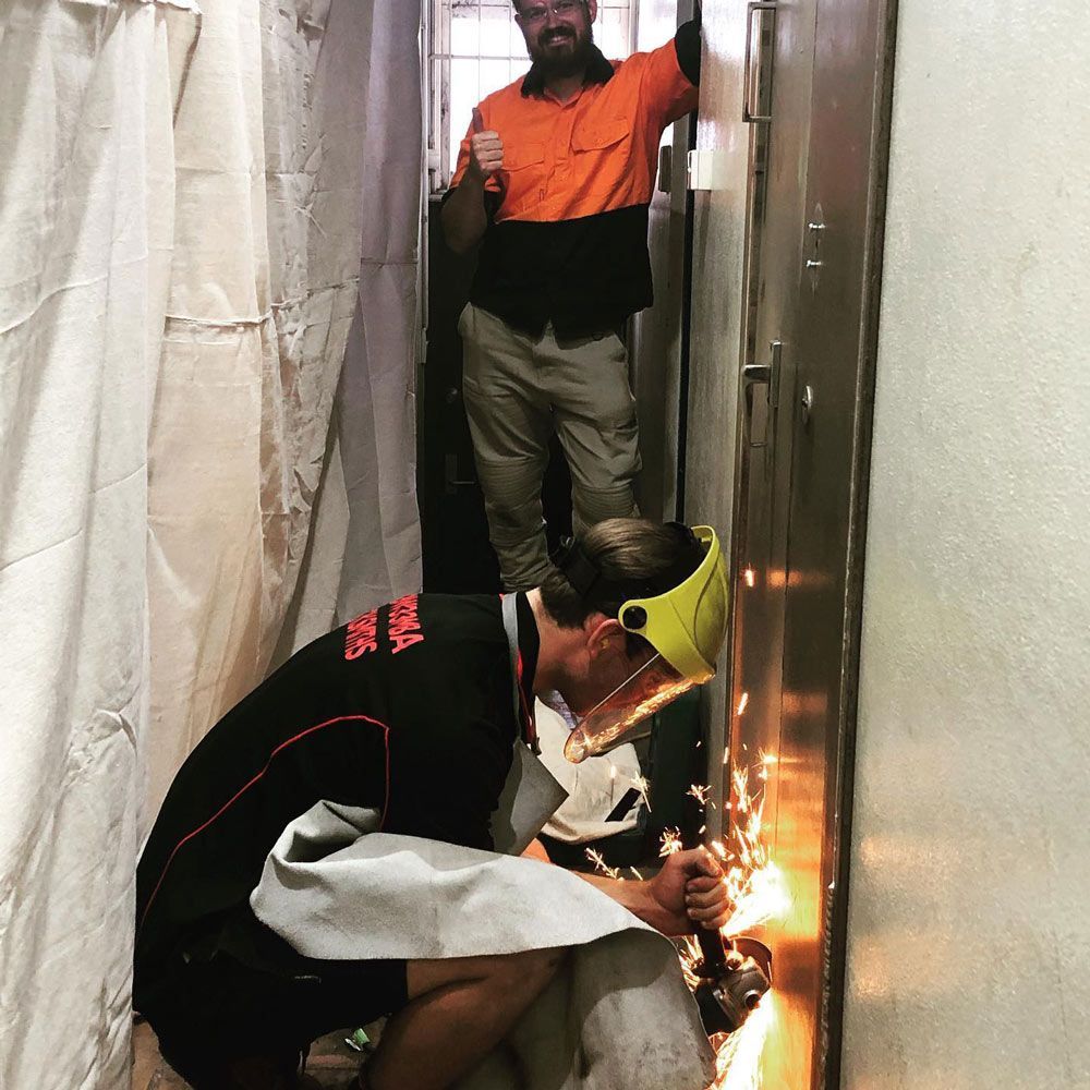 A Man Is Working with The Door — Toowoomba Locksmiths in Toowoomba City, QLD