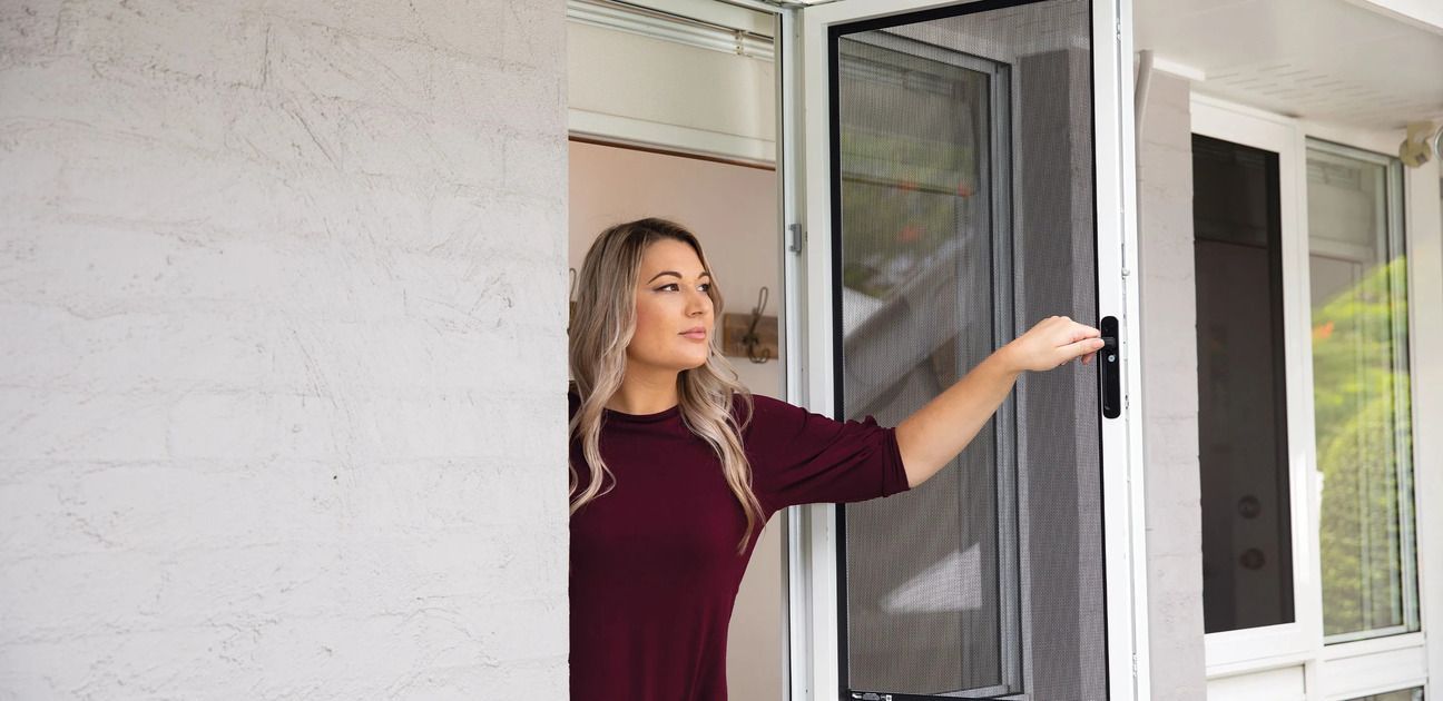 A Woman Is Opening a Screen Door — Toowoomba Locksmiths in Toowoomba City, QLD