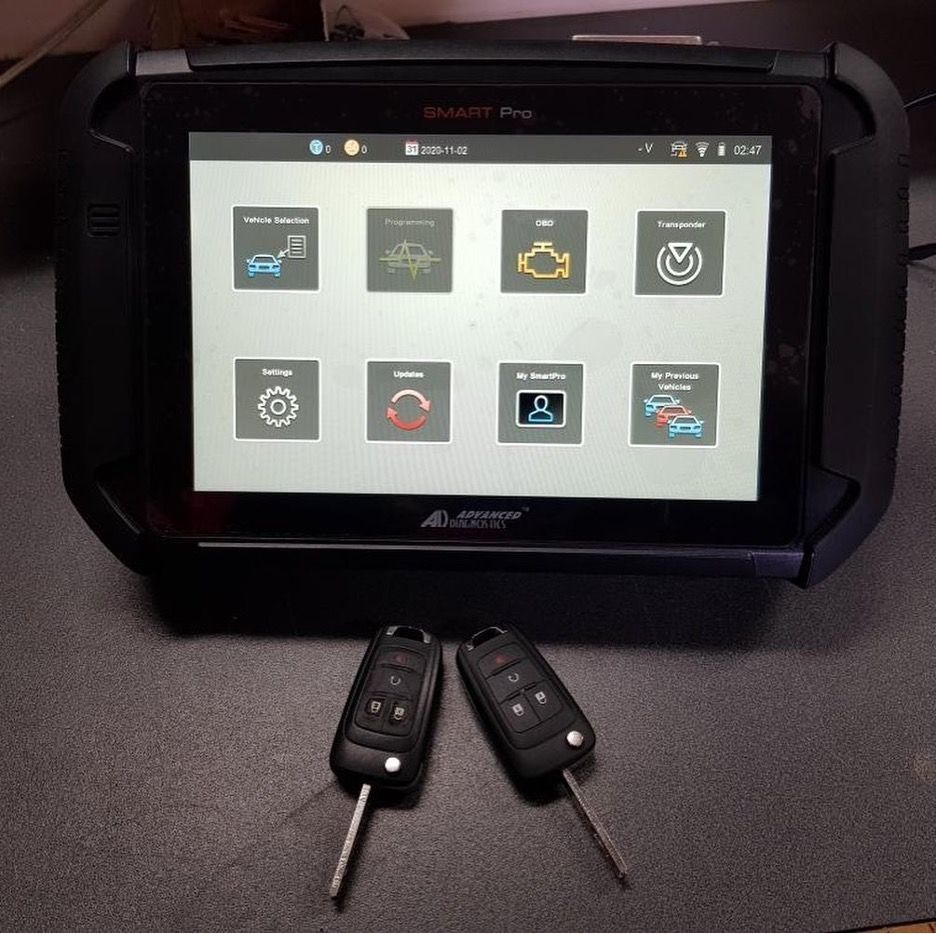 Two Car Keys Are Sitting Next to A Tablet — Toowoomba Locksmiths in Toowoomba City, QLD