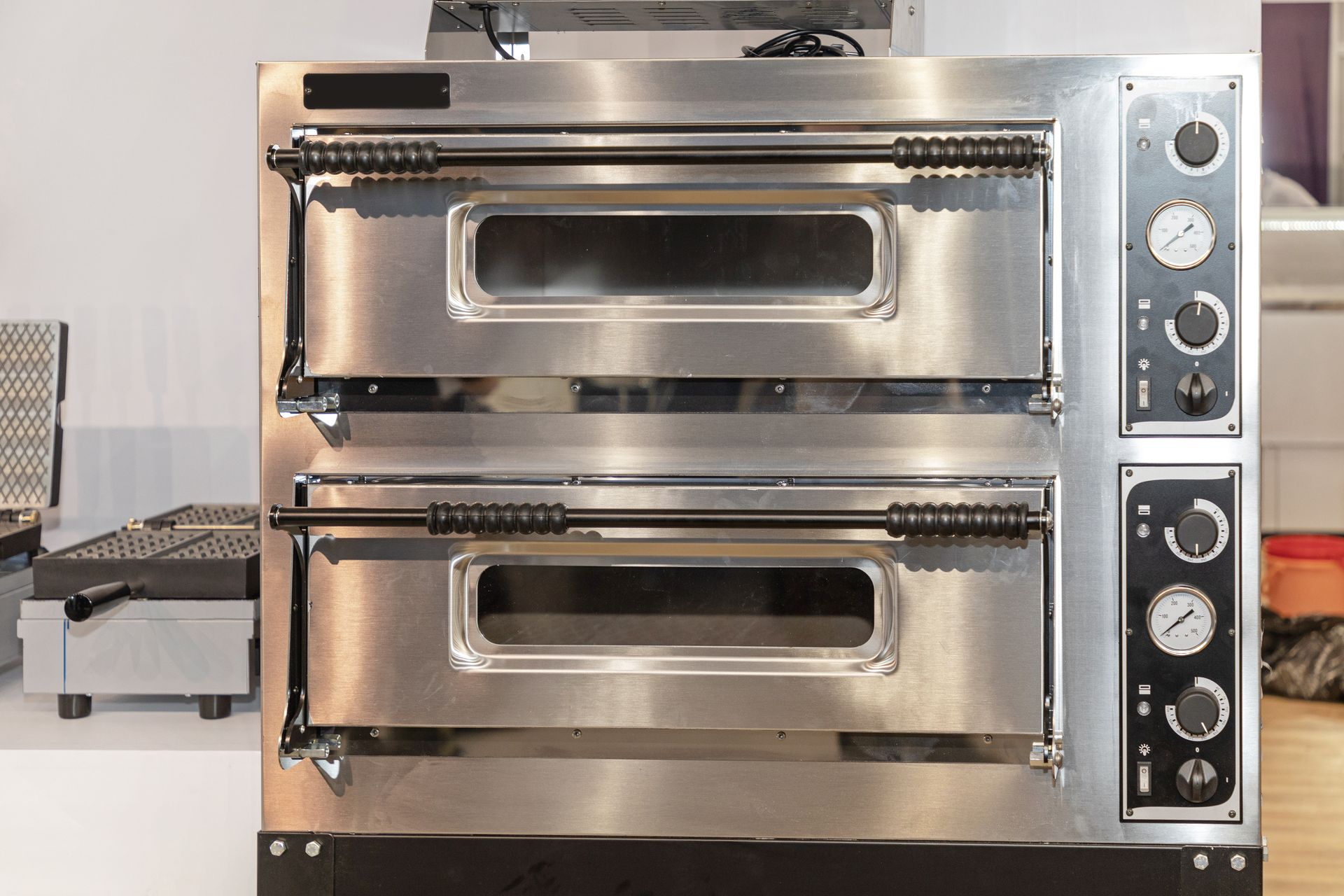 Stacked stainless steel commercial ovens with black control panels.