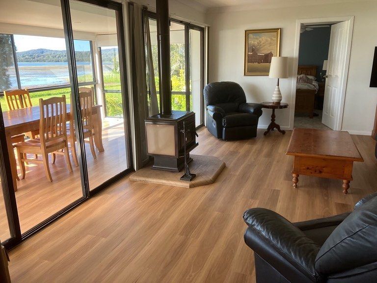 Living room with lake view, sliding glass doors, leather chairs, fireplace, and wooden coffee table