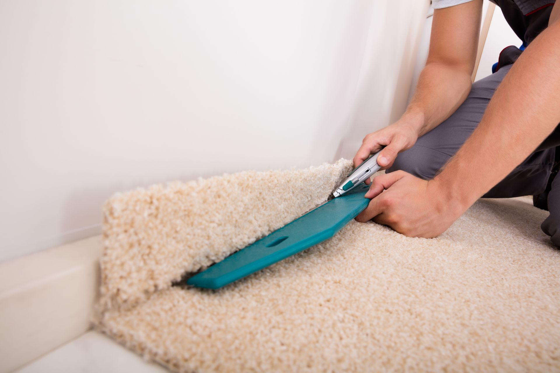 A person is cutting a carpet with a cutter.